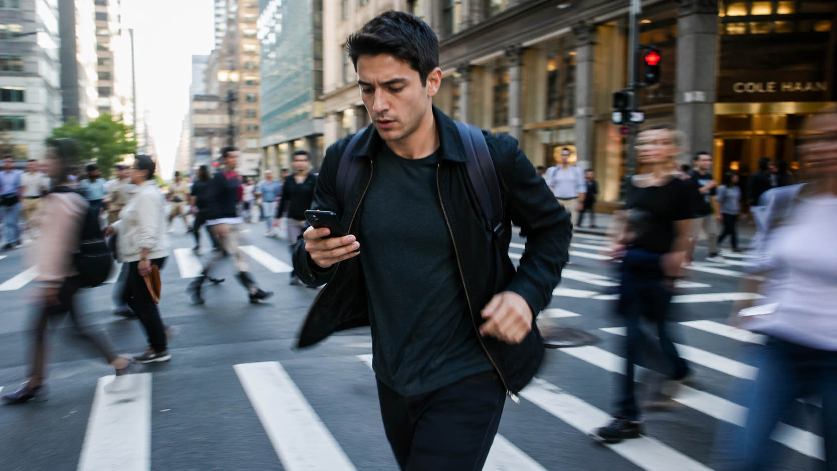 Mladić brzo reaguje dok gleda u telefon u gradskoj gužvi.